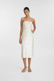 A woman modeling a strapless, knee-length white sequined dress against a light gray studio background.